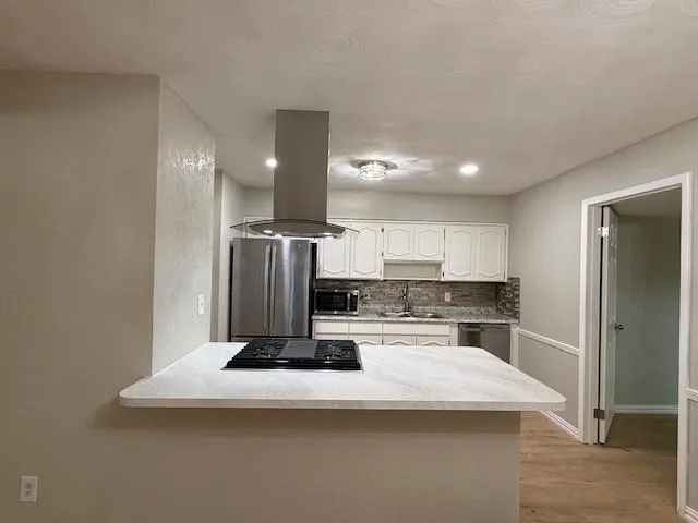 a kitchen with kitchen island a stove a refrigerator and a sink