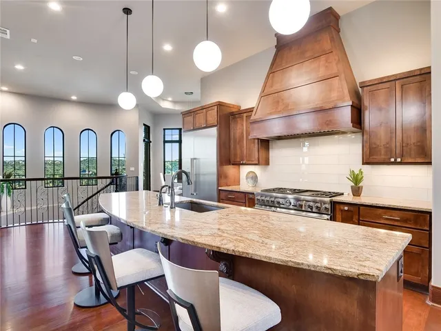 a kitchen with granite countertop a stove a sink a dining table and chairs with wooden floor