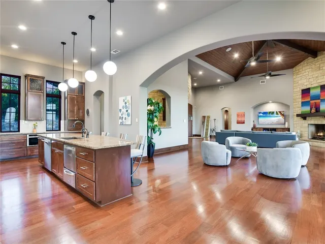a large white kitchen with a large island oven a stove and a wooden floor
