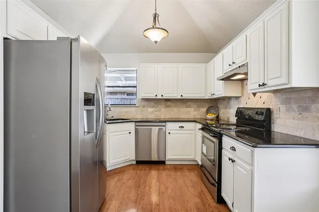 a kitchen with stainless steel appliances granite countertop a refrigerator and a stove top oven