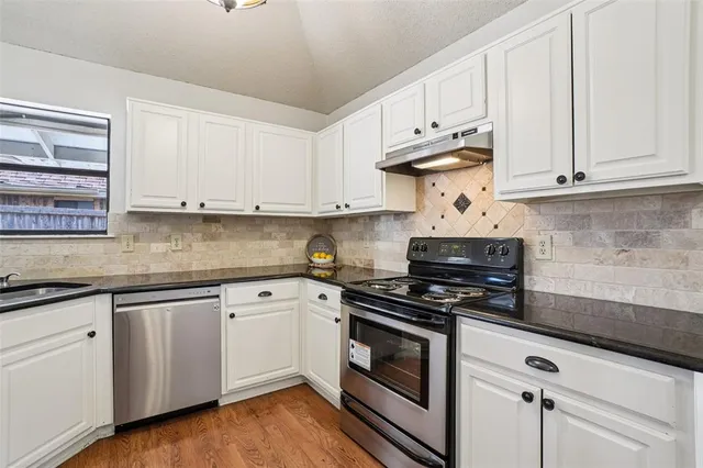 a kitchen with granite countertop white cabinets and white appliances