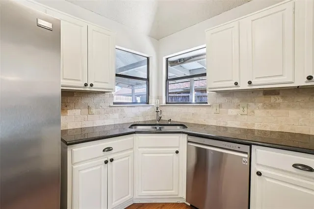 a kitchen with stainless steel appliances granite countertop white cabinets and a sink