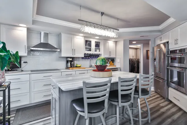 a kitchen with stainless steel appliances kitchen island granite countertop a dining table chairs and white cabinets