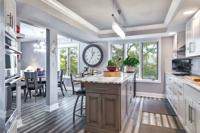 a kitchen with a wooden table chairs cabinets and a large window