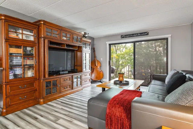 a living room with furniture a flat screen tv and floor to ceiling window