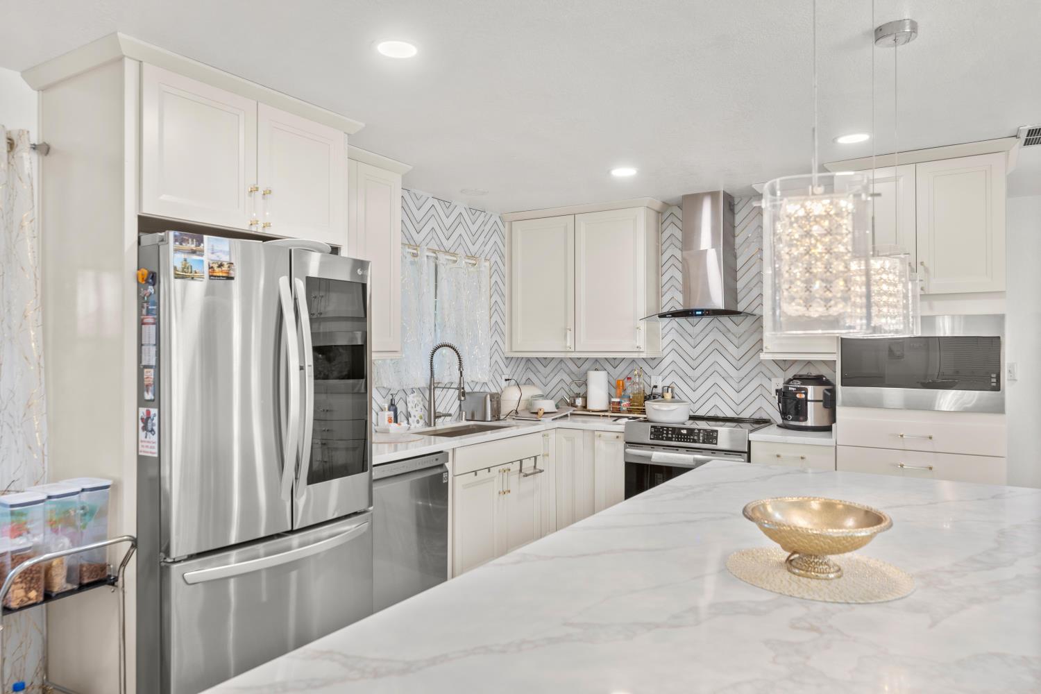 8850 Bader Road Elk Grove, CA 95624 - Photo 18 of 43 a kitchen with white cabinets and stainless steel appliances