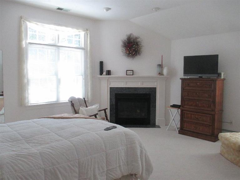 27 Forest Hills Road Cotuit, MA 02635 - Photo 14 of 28 a bedroom with a bed and a fireplace