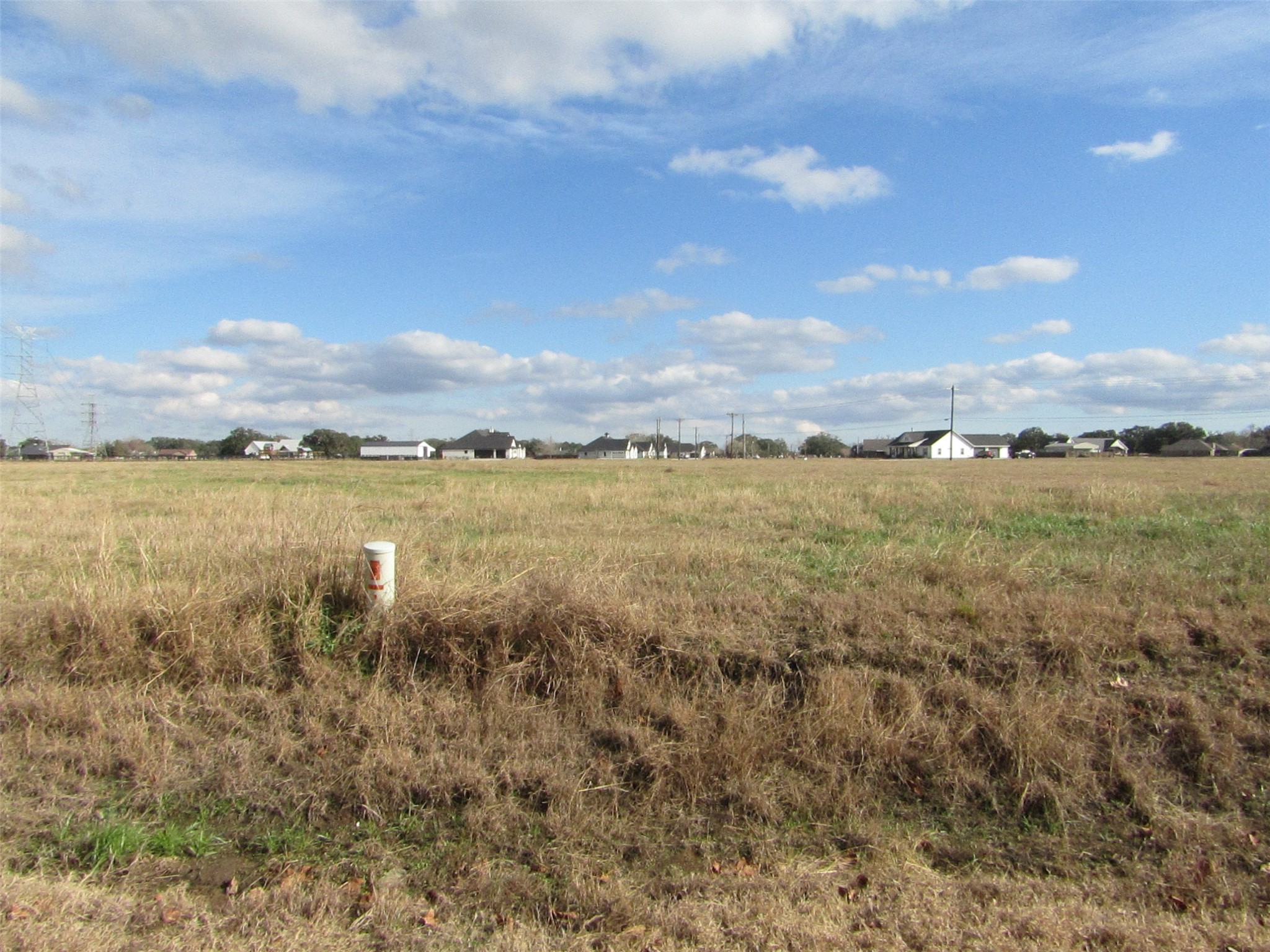 707 Winchester Trail Angleton, TX 77515 - Photo 7 of 8 Expansive open lot with grassy fields, offering potential for development. Surrounded by distant homes, providing a balance of seclusion and community. Ideal for building a custom home in a peaceful setting.