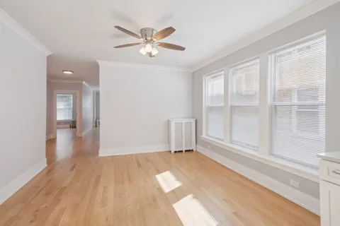 a view of empty room with wooden floor and fan