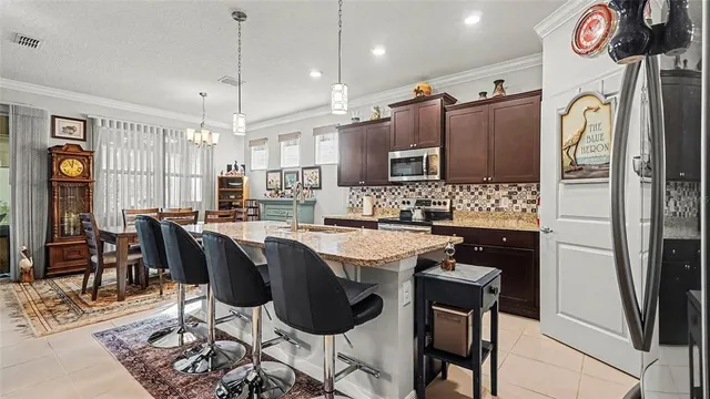 a kitchen with stainless steel appliances granite countertop a stove a refrigerator a oven a sink a dining table and chairs with wooden floor