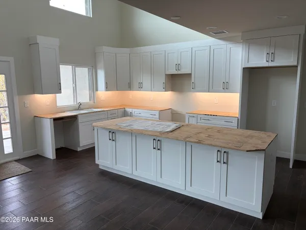 a kitchen with kitchen island granite countertop a sink cabinets and wooden floor
