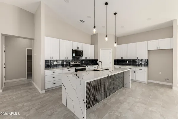a kitchen with stainless steel appliances kitchen island granite countertop a refrigerator a stove a sink and white cabinets