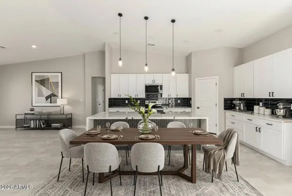 a kitchen with stainless steel appliances granite countertop a table chairs stove and white cabinets