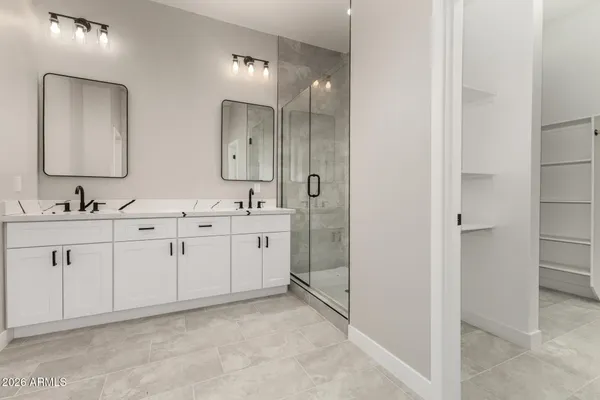 a spacious bathroom with a double vanity sink a mirror and a shower
