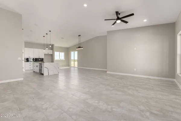 a view of a livingroom with a ceiling fan and kitchen space