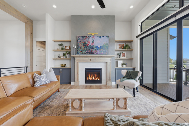 4331 West 475 South West Point, UT 84015 - Photo 6 of 46 Gas fireplace with stone mantel, built-in shelving, wood-finish flooring, exposed wood beam, and sliding glass doors to outdoor deck