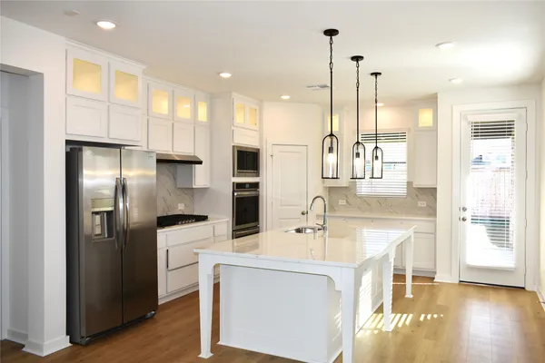 a kitchen with kitchen island granite countertop a sink a counter and stainless steel appliances