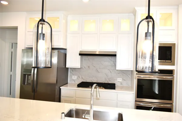 a kitchen with stainless steel appliances kitchen island granite countertop a refrigerator a stove and a sink with wooden floor