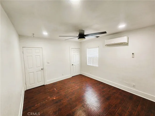 an empty room with wooden floor a ceiling fan and windows