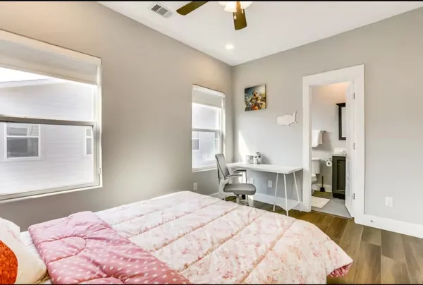a bedroom with a bed a dresser and potted plant