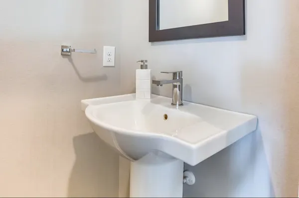 a white sink sitting under a bathroom mirror
