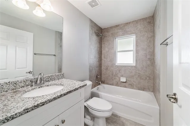 a bathroom with a granite countertop toilet a sink and a bathtub