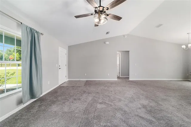 an empty room with chandelier fan and windows