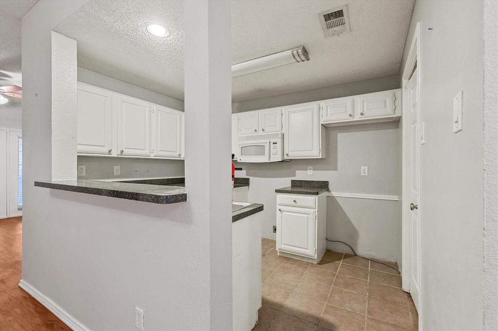 12660 Hillcrest Road, Unit 7103 Dallas, TX 75230 - Photo 6 of 14 a kitchen with white cabinets and white appliances