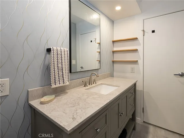 a bathroom with a granite countertop sink and a mirror