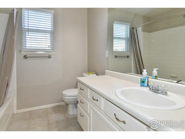 a bathroom with a toilet a sink a mirror and a window