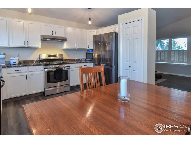 a kitchen with stainless steel appliances granite countertop a refrigerator a stove a sink and a granite counter tops with wooden floors