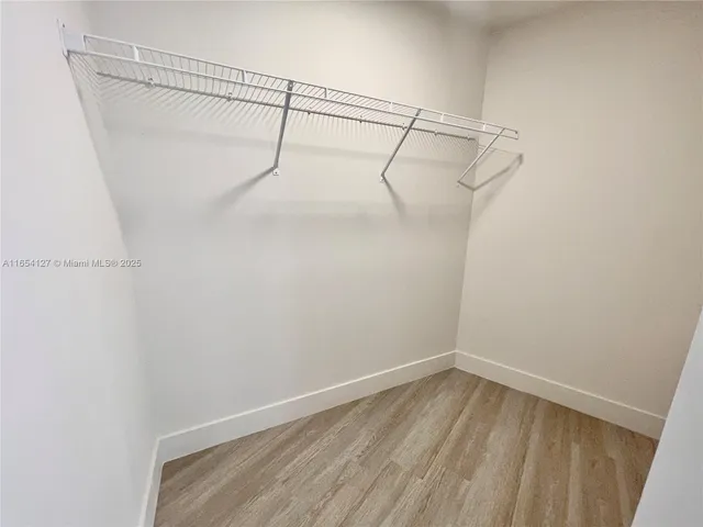 a view of a refrigerator in kitchen and an empty room