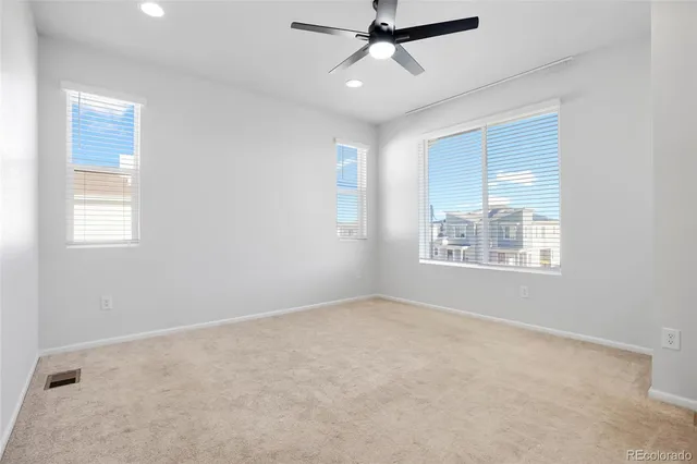 an empty room with windows and fan