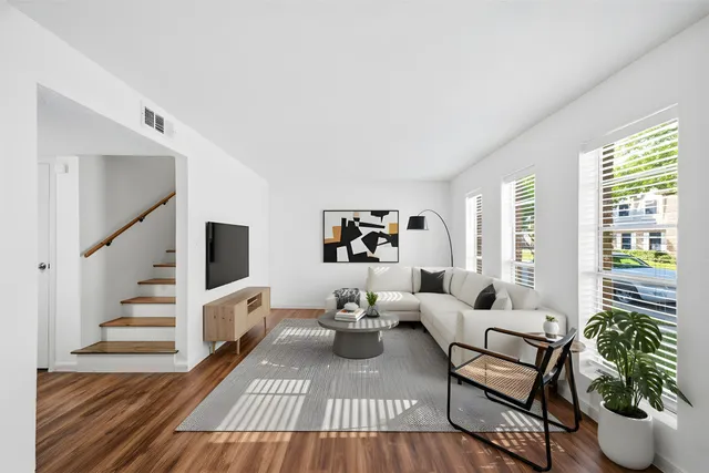 a living room with furniture a flat screen tv and a potted plant
