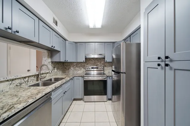a kitchen with stainless steel appliances granite countertop a sink stove and refrigerator