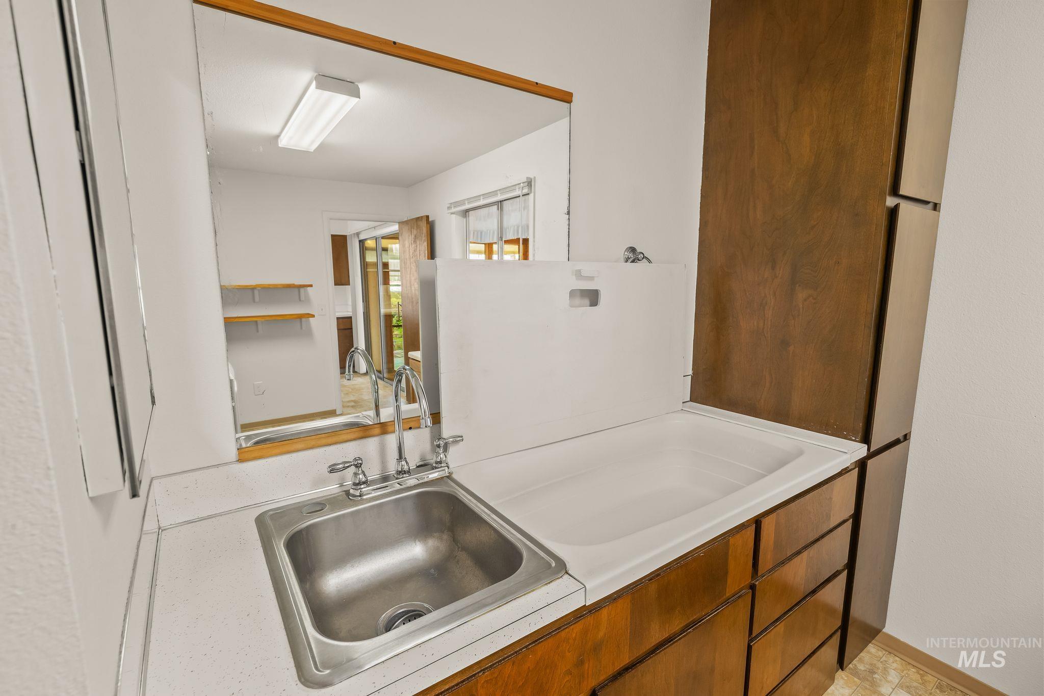 1721 3rd Street Lewiston, ID 83501 - Photo 35 of 45 Utility room featuring a stainless steel sink, solid surface countertop, wood cabinetry, and a built-in laundry tub