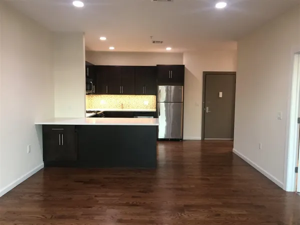 a view of kitchen with refrigerator and wooden floor