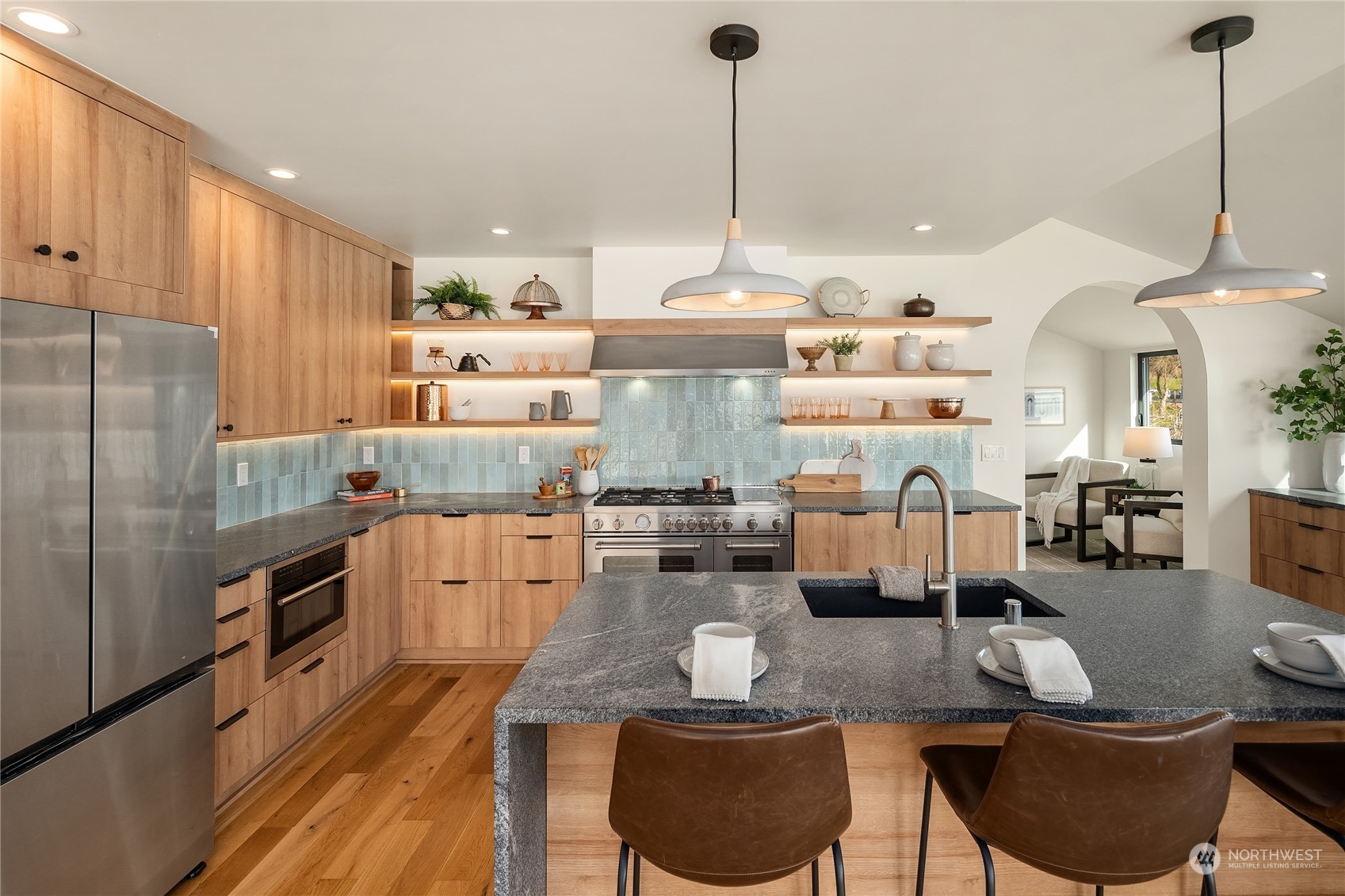 a kitchen with stainless steel appliances kitchen island granite countertop a table chairs stove and refrigerator