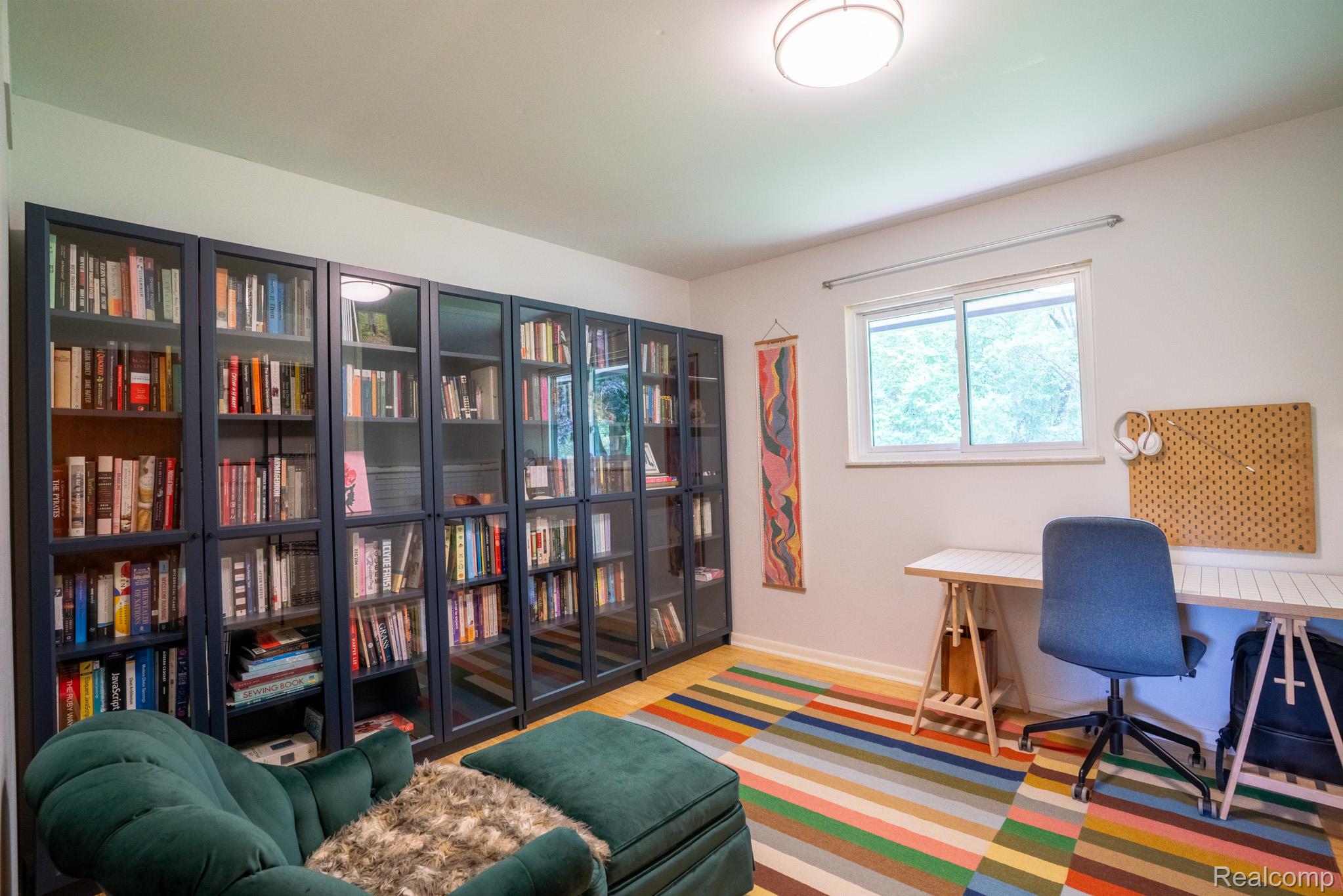 7333 Toma Road Dexter, MI 48130 - Photo 30 of 45 featuring extensive built-in shelving with glass doors, a large window, light wood-finish flooring, and a flush-mount ceiling light