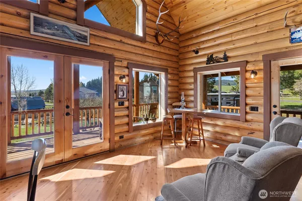 a living room with furniture a floor to ceiling window and wooden floor