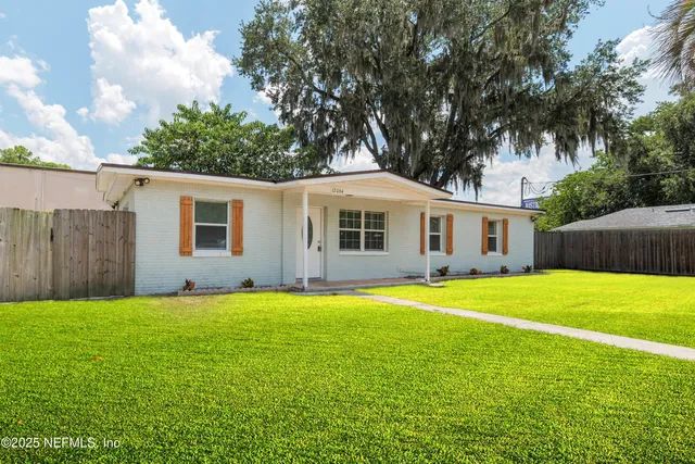 a view of a yard with a house and a large tree