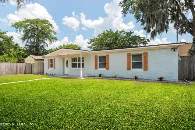a view of a house with a backyard and a large tree