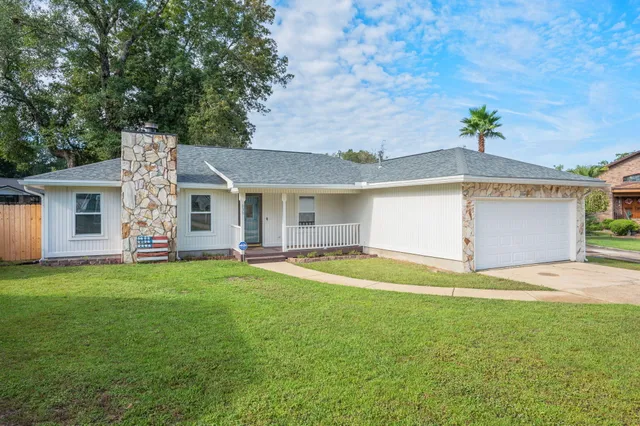 a view of a house with a yard and a large tree