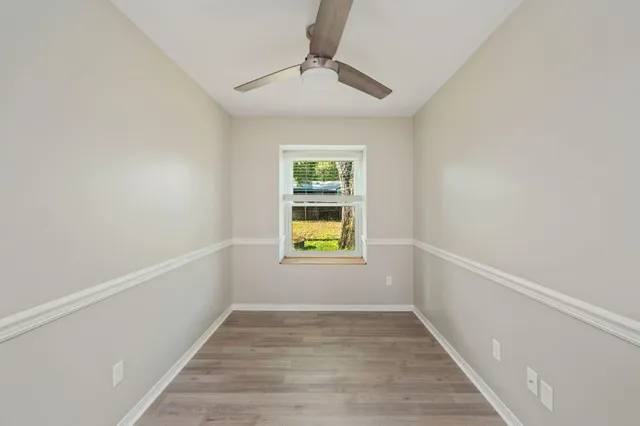 a view of an empty room with window and wooden floor