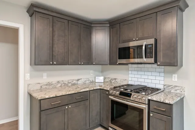 a kitchen with granite countertop a stove top oven microwave and cabinets