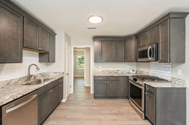 a kitchen with stainless steel appliances granite countertop a sink stove microwave and refrigerator