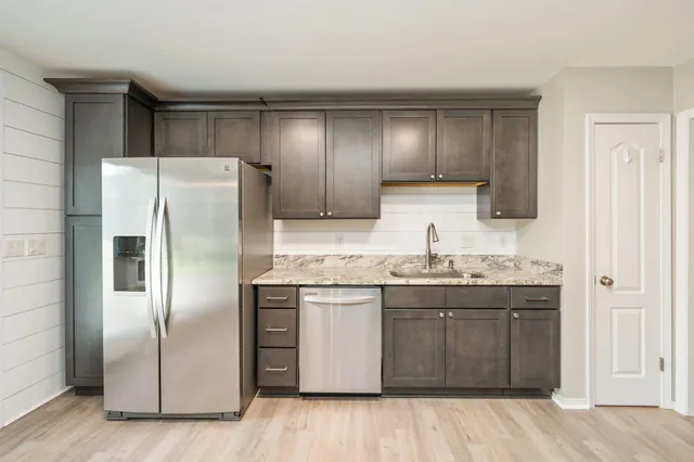 a kitchen with stainless steel appliances granite countertop a refrigerator and a sink