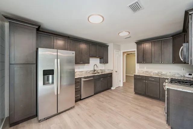 a large kitchen with stainless steel appliances granite countertop a refrigerator stove and sink