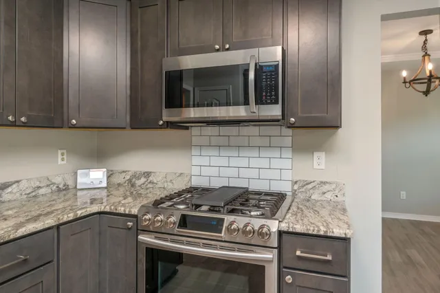 a kitchen with granite countertop cabinets and steel stove top oven