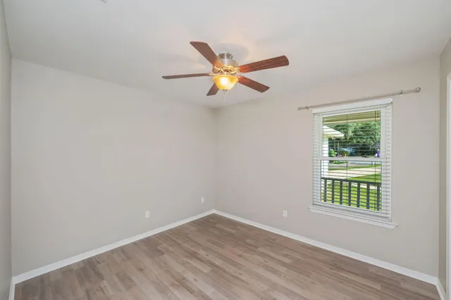 a view of an empty room with window and wooden floor